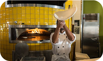 Cook flipping pizza dough in the air